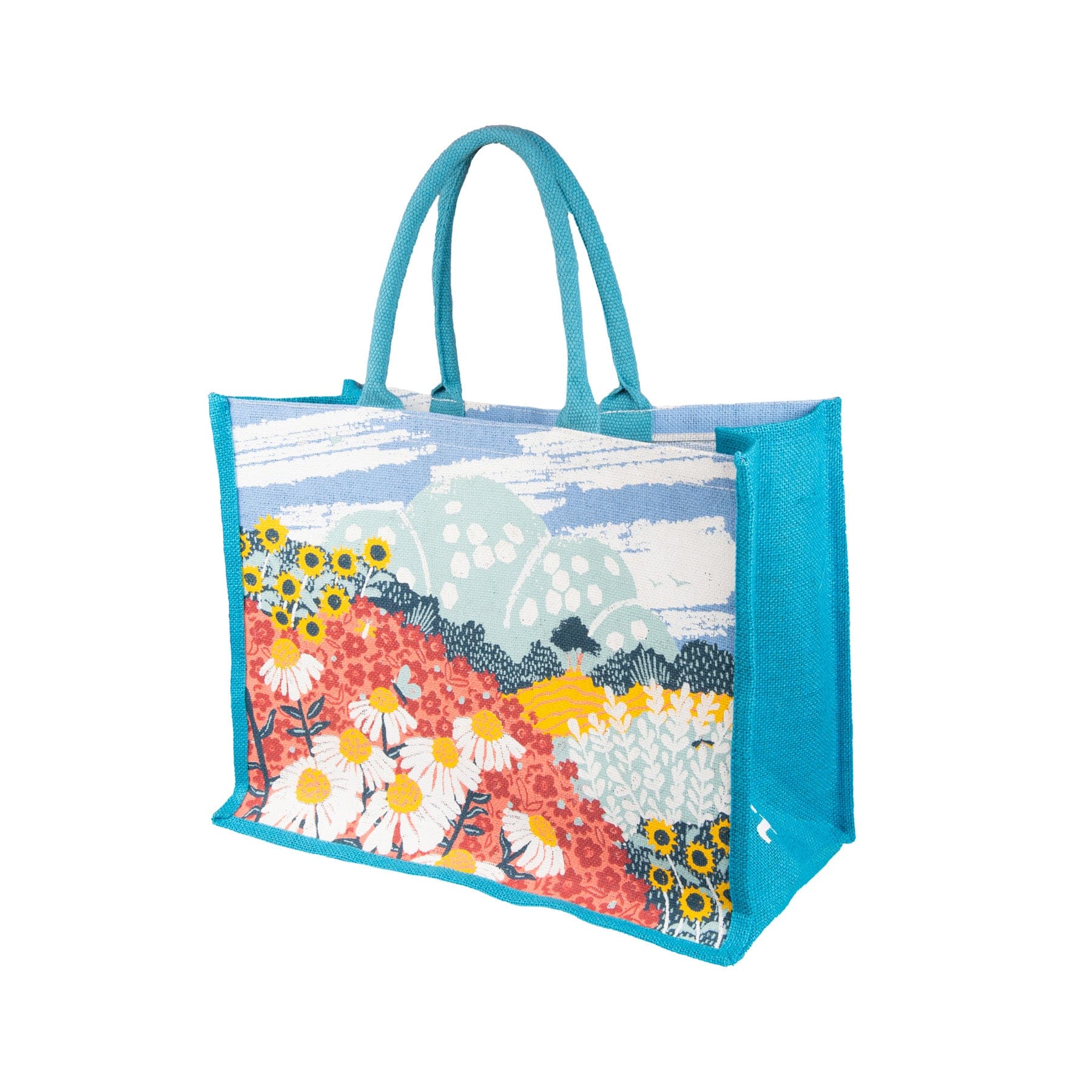 Colorful floral tote bag with blue handles on white background, featuring daisy and sunflower print with scenic landscape design