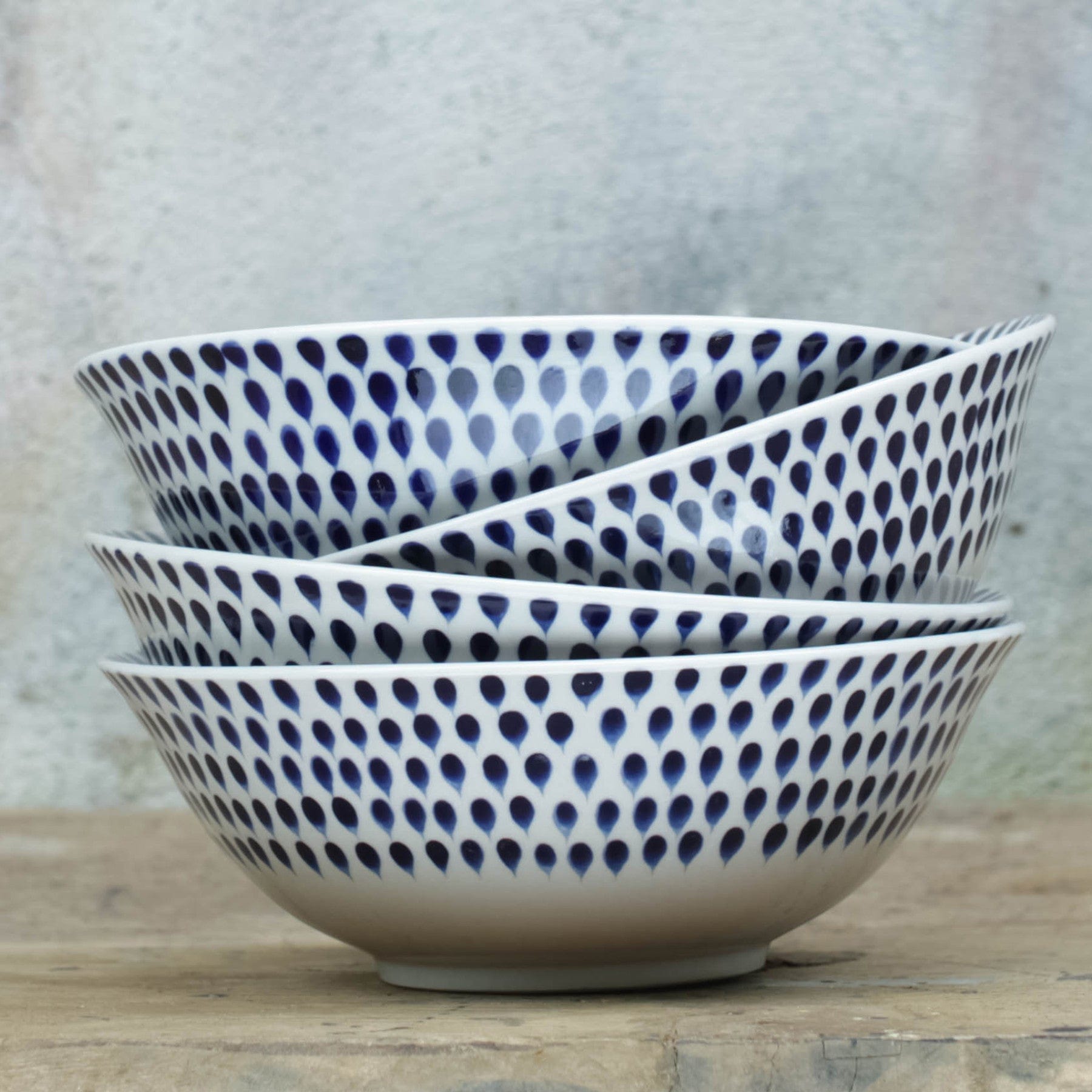 Stack of blue and white patterned ceramic bowls on a wooden surface with a textured background