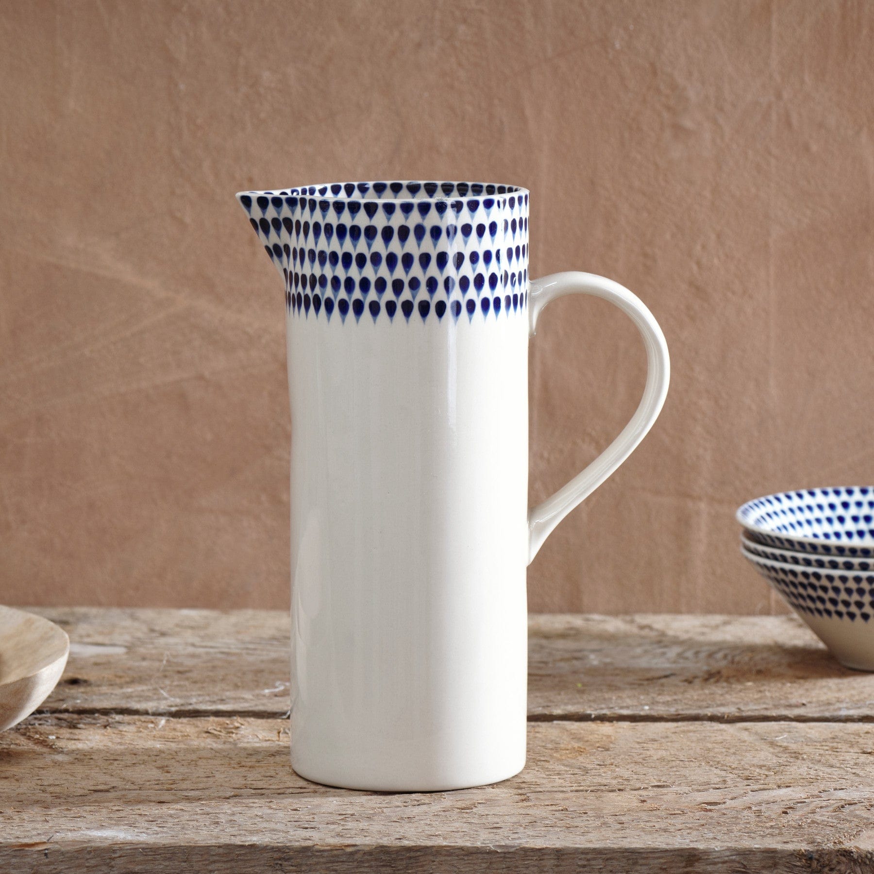 Ceramic pitcher with blue dot pattern on rustic wooden table, kitchenware concept, elegant stoneware, home decor accessory