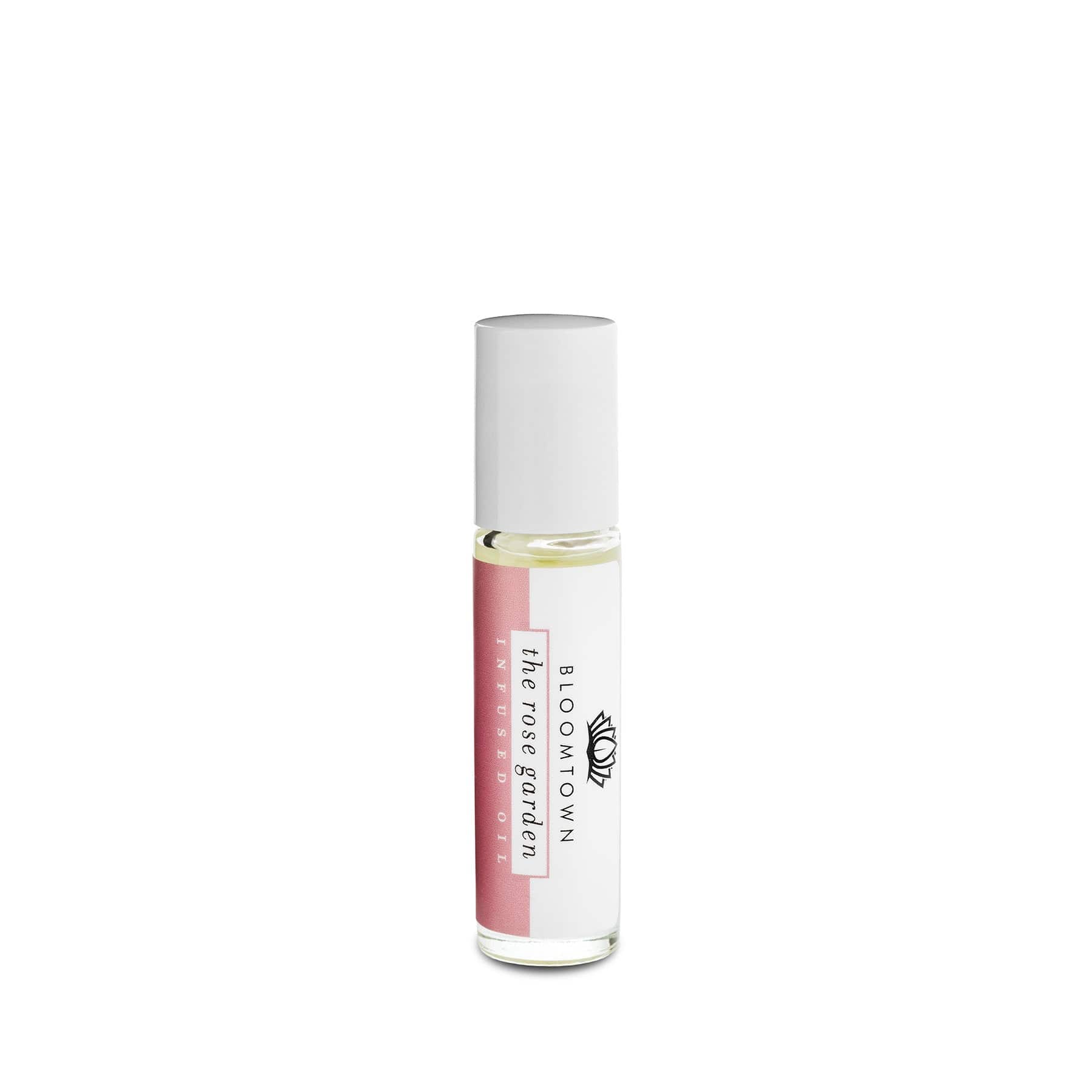 Alt text: Roll-on perfume oil in a glass bottle with a white cap and labeled "The Rose Garden" by Bloomtown, isolated on a white background.