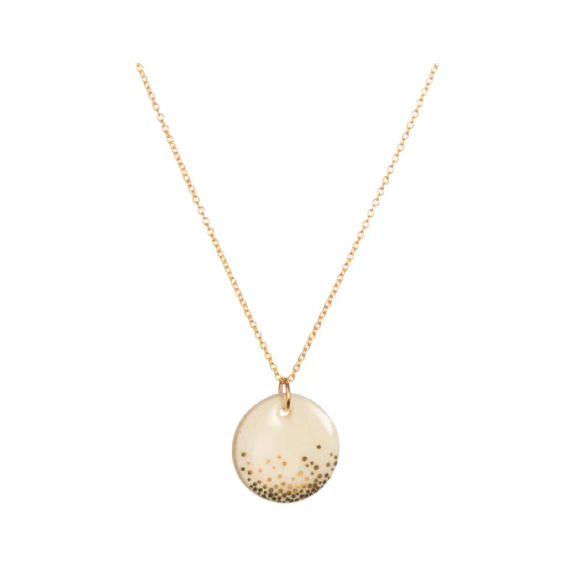 Elegant gold necklace with round pendant containing speckled details on a white background.