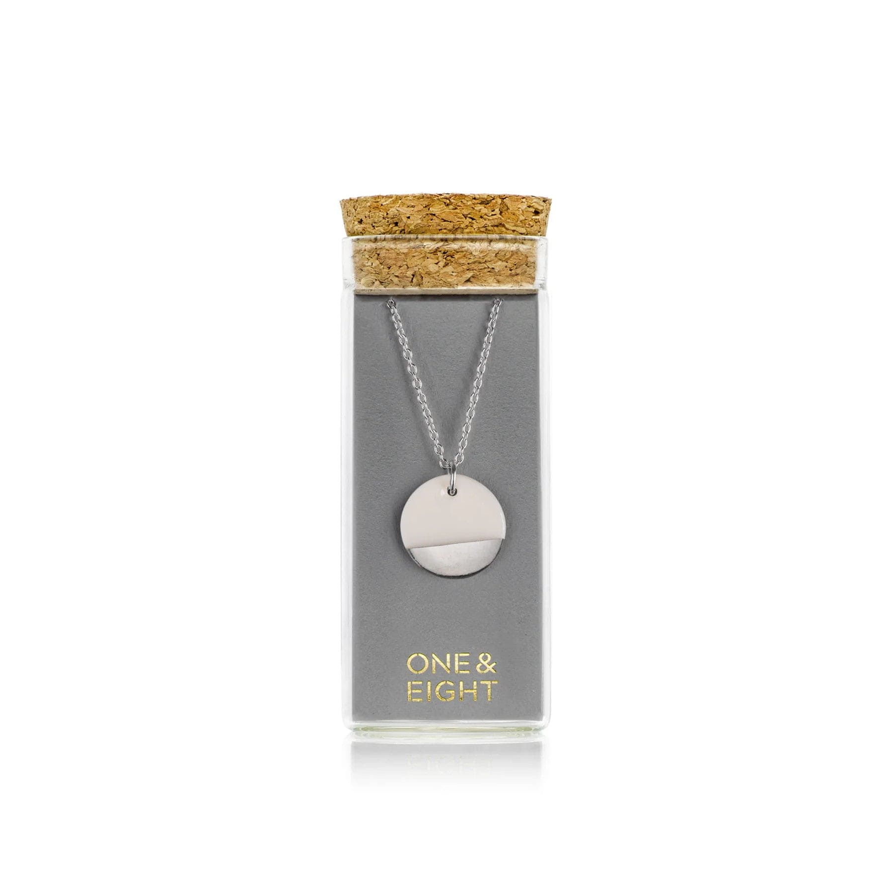 Circular pendant necklace displayed in a glass vial packaging with cork stopper and One & Eight branding.