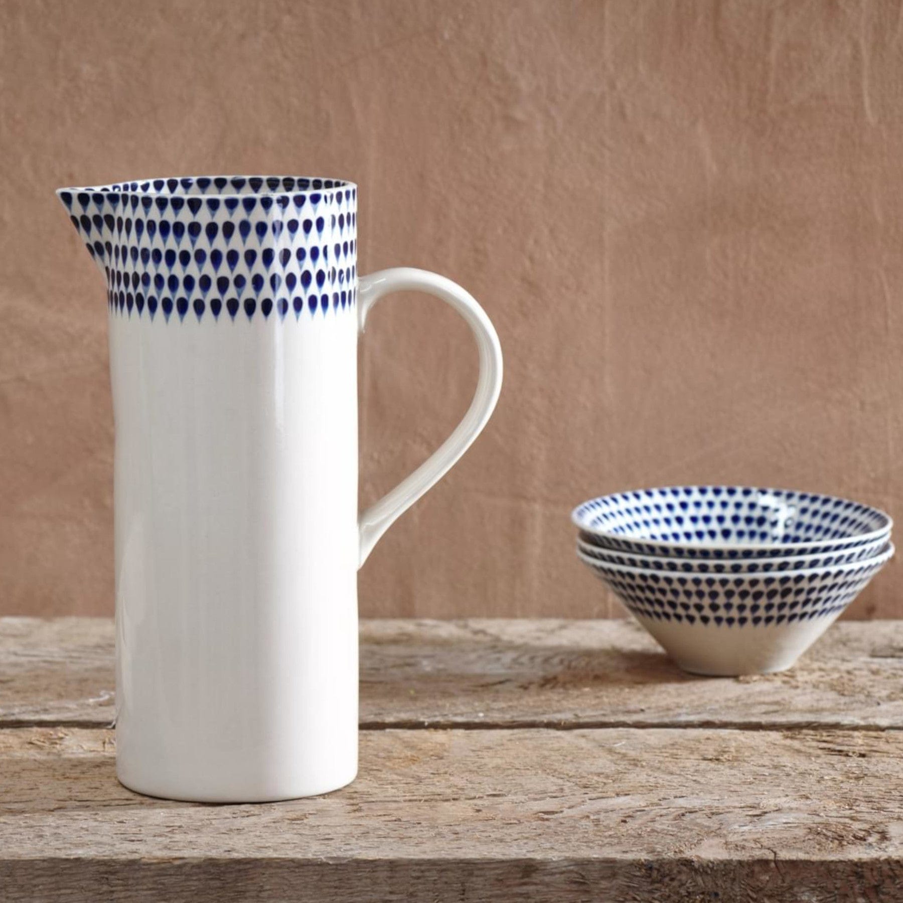 Ceramic pitcher and bowl with blue dot pattern on rustic wooden table, kitchenware, pottery, home decor