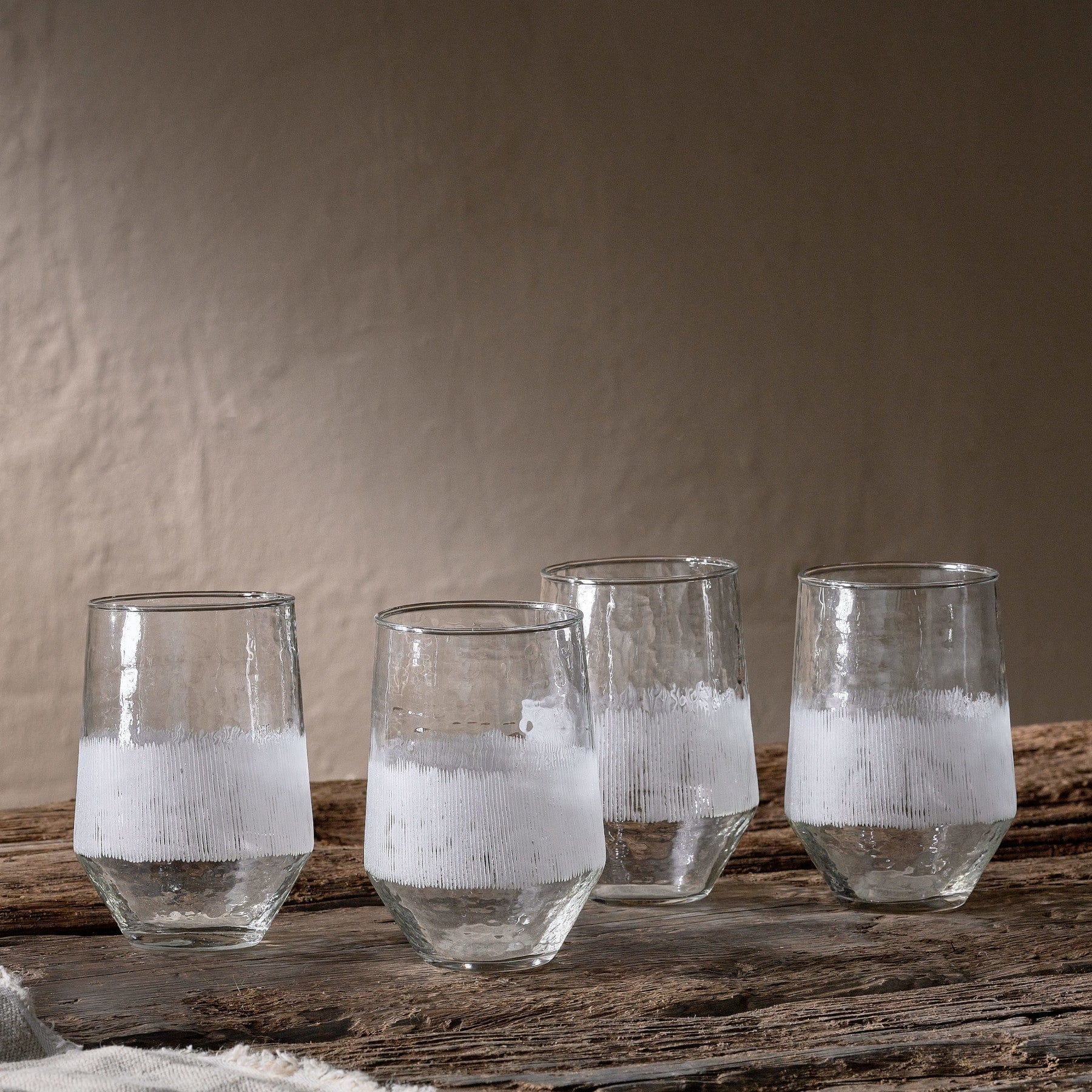 Water glasses with condensation on rustic wooden table against textured gray background.