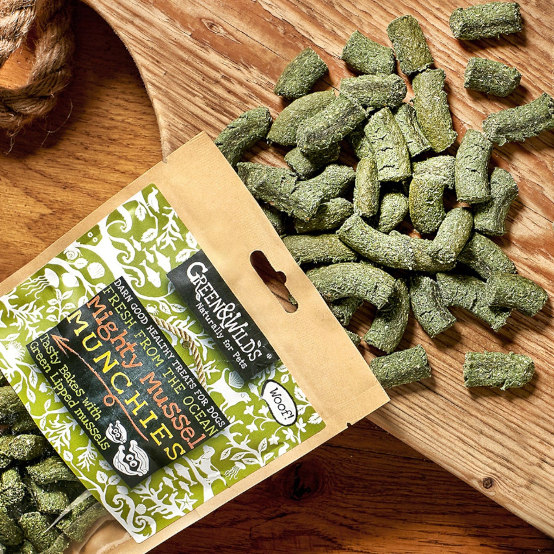 Organic pet food Greenhill's Mighty Munchies with fresh farm-grown mushrooms, peas and parsley on wooden background, eco-friendly packaging, vegan dog treats spilled from bag.
