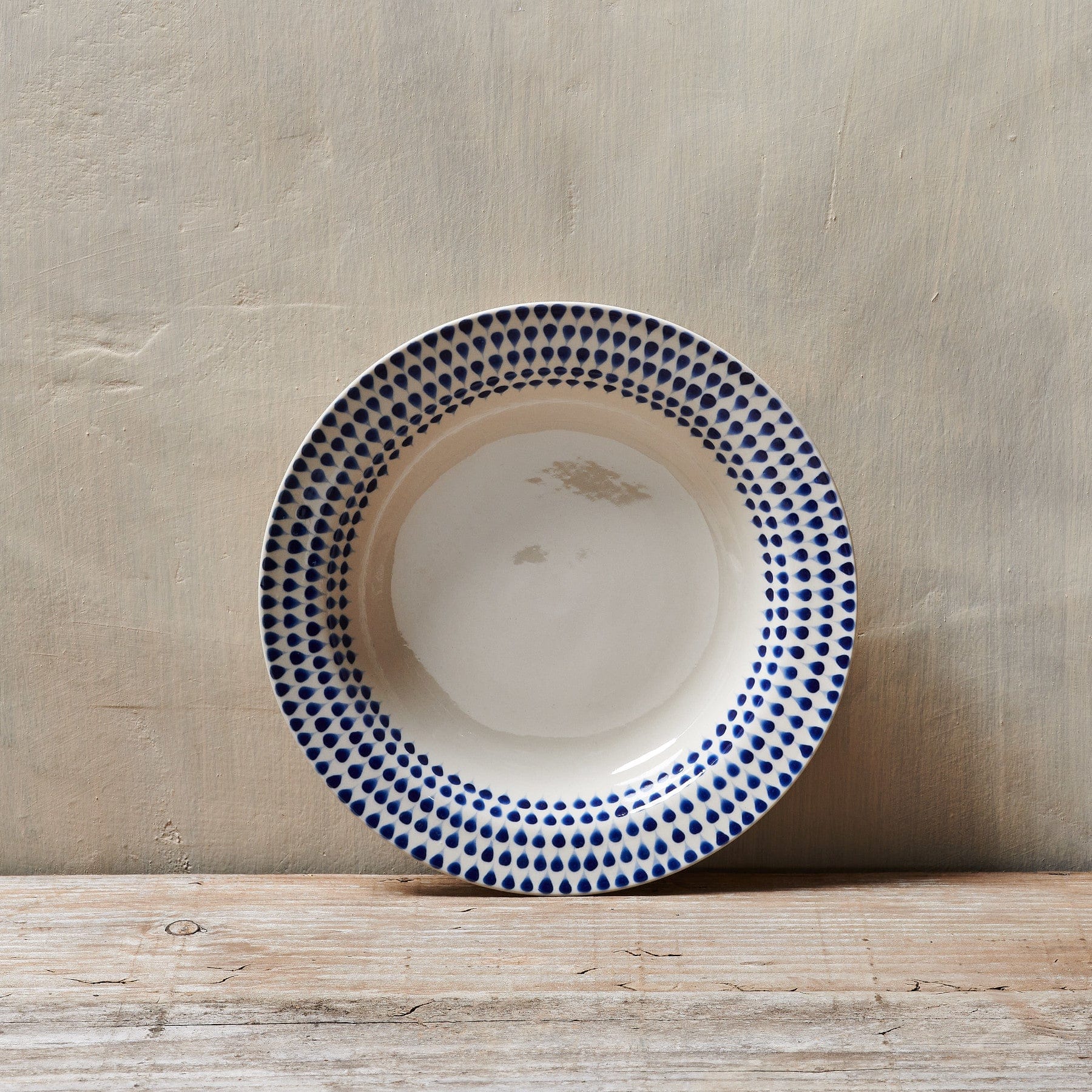 Blue and white patterned ceramic plate on a rustic wooden surface against a neutral background