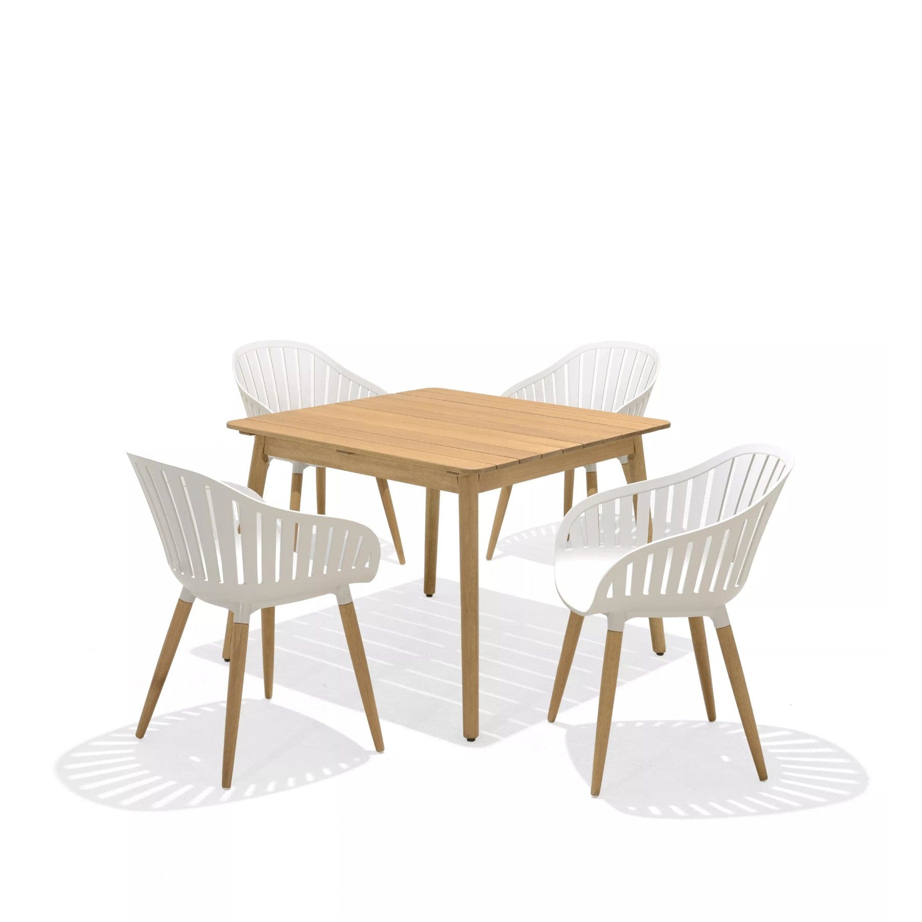 Modern wooden dining table with four white chairs on a white background