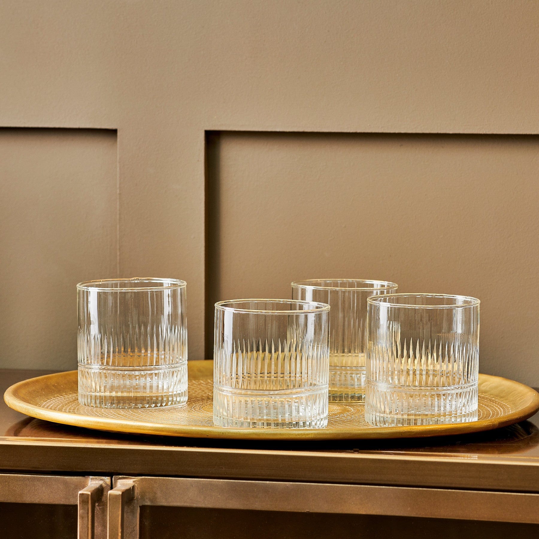 Elegant crystal whiskey glasses set on a golden tray on wooden table, home bar accessories, luxury glassware, interior design details