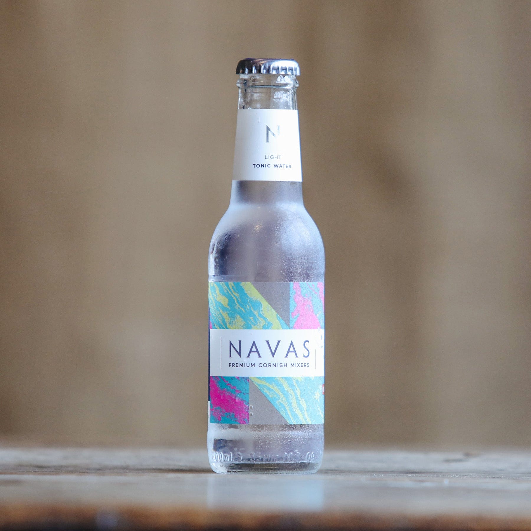 Chilled bottle of Navas light tonic water on wooden surface with colorful label design and blurred background