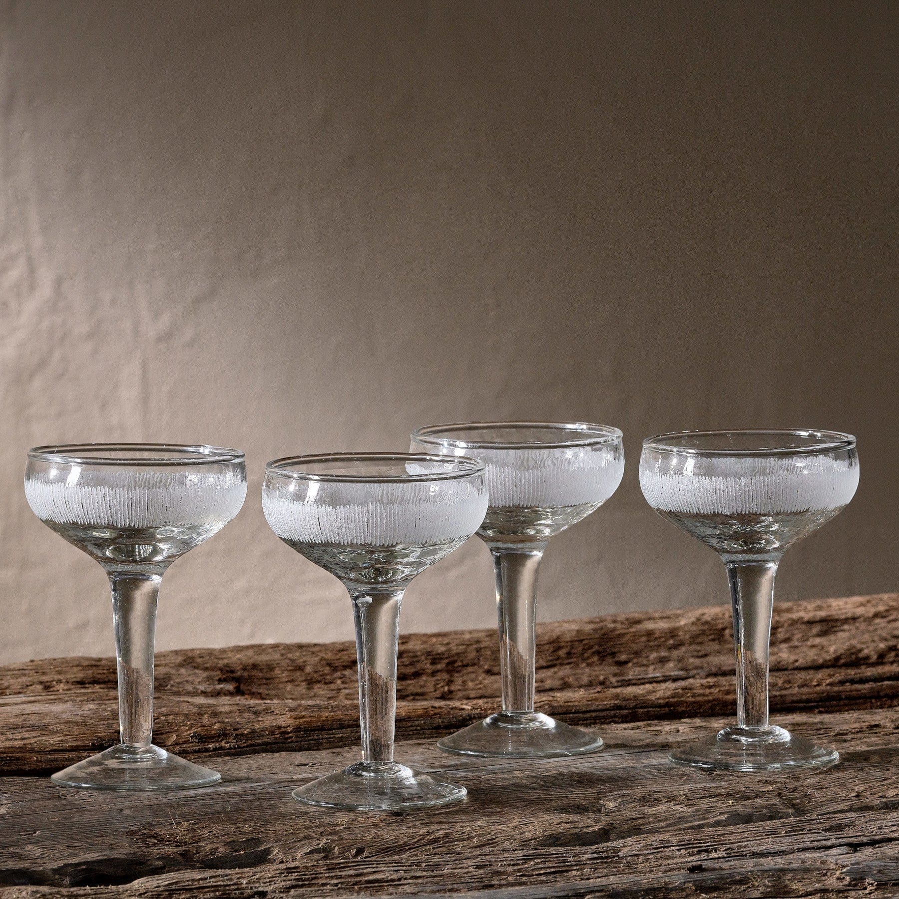 Vintage crystal champagne coupe glasses on rustic wooden surface with textured gray background