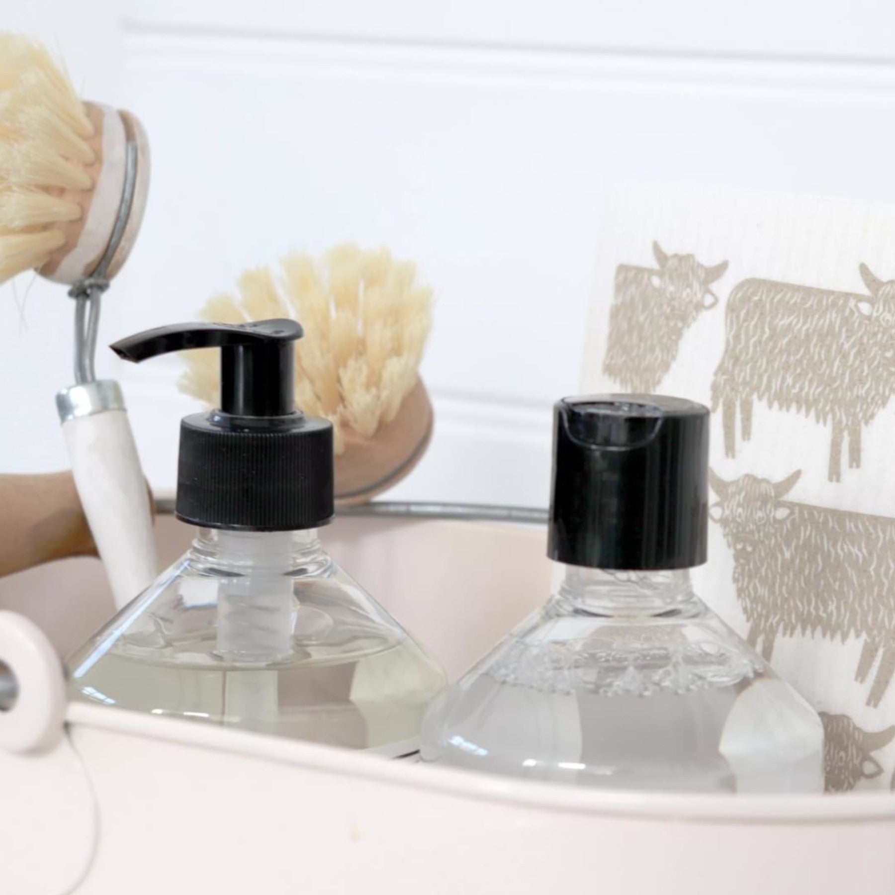 Bathroom counter with clear glass soap dispensers, natural sea sponge, and animal print towel in a modern home setting