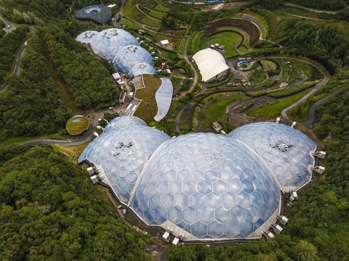 Aerial view of the Eden Project biomes amongst greenery, large domed eco-friendly structures, environmental conservation, sustainable architecture, tourist attraction in Cornwall, UK.