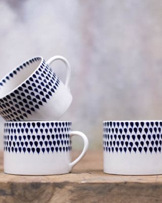 Patterned ceramic cups on wooden surface, one cup stacked atop another, with a soft-focus background