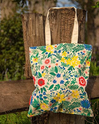 Floral tote bag hanging on a wooden fence outdoors, vibrant print, reusable shopping bag, eco-friendly, accessory, fashion, nature background